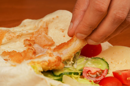Cooking chicken roll. Tortilla wrap with fried chicken meat and vegetables, close up. Shawarma tomato, cucumber, onion, lettuce and chicken meat. Fast food. Junk food. Eating. Food. Delicious.の写真素材
