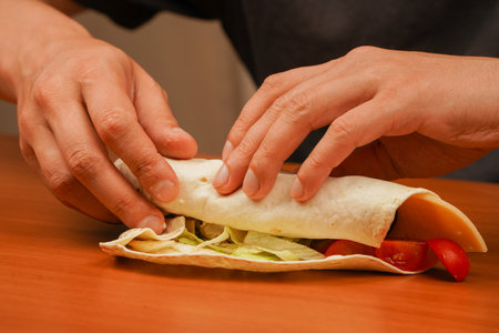 Shawarma tomato, cucumber, onion, lettuce and chicken meat. Fast food. Junk food. Eating. Food. Delicious. Cooking chicken roll. Tortilla wrap with fried chicken meat and vegetables, close up.の写真素材