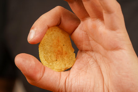 Unhealthy lifestyle. Man eating potato chips. Fast food. Junk food. Hands hold potato chip. Calories. Obesity. American food. Okay sign.の写真素材
