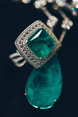 Emeralds close-up in jewelry. Beautiful ring of earrings with green Emerald and Diamonds gemstones....