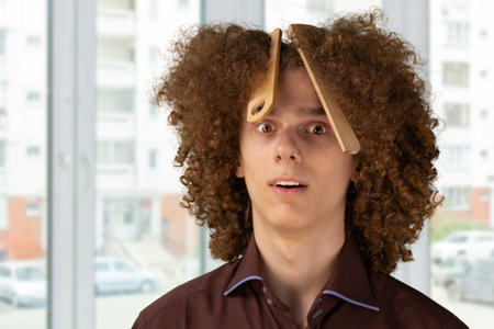 Closeup photo of curly young guy. Smiling curly haired young man with brushes in his hair, studio...
