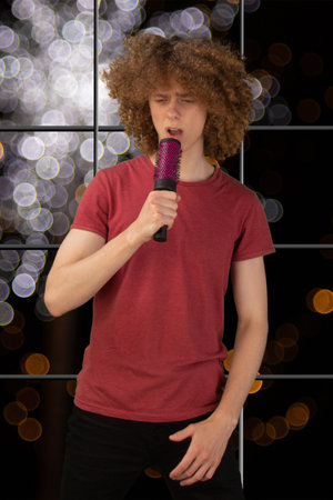 Joyful young European man, confidently wielding a brush as a mic, singing a song isolated on a nice background.の写真素材
