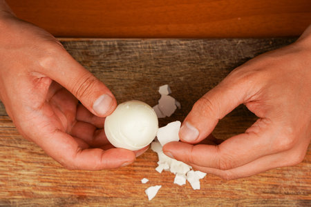 Preparing food. Horizontal photo. Vegetarian. Man holding egg over wooden board. Boiled egg....