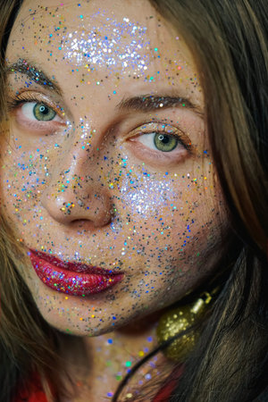 Close-up portrait of a beautiful girl with festive make-up. Perfect red lip design. Gold and glitter...