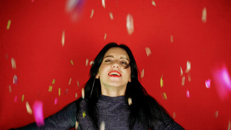 Cheerful beautiful brunette girl blowing confetti from her hands. Celebration of the holiday....