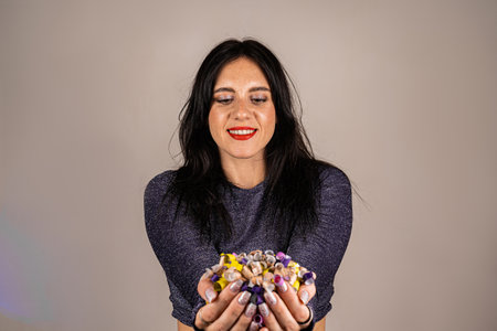 Cheerful beautiful brunette girl blowing confetti from her hands. Celebration of the holiday. Festive atmosphere. Fun event.の写真素材