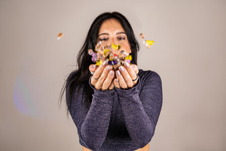 Cheerful beautiful brunette girl blowing confetti from her hands. Celebration of the holiday. Festive New Years atmosphere. Fun event. Christmas concept.の写真素材