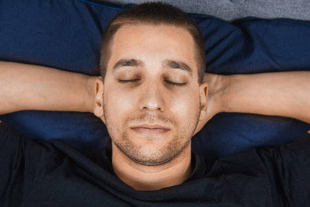 Top view of a handsome young man sleeping comfortably on the bed in his bedroom at night. Bachelor...