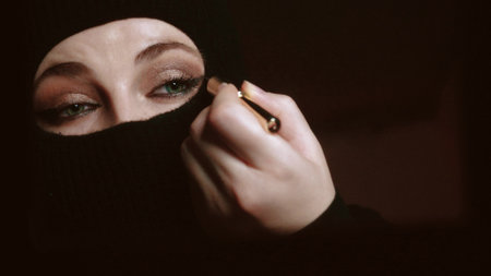 Portrait of a beautiful young Muslim woman in a hijab and with facial makeup with a mirror on a uniform background. Use for fashion and beauty concept.の写真素材