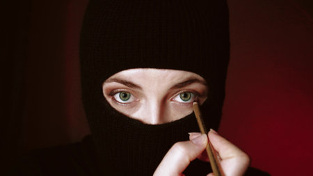 Fashionable beautiful girl in a balaclava. Fashion mask on beautiful female models. Hat style. Girl in a black balaclava. Fashionable mask on a beautiful woman with colored make-up.の写真素材