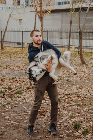 A boy plays with a dog in the park. A warmly dressed man with a fluffy dog in his arms.の写真素材