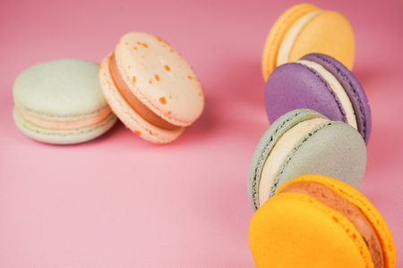 Multi-colored French macarons, neatly arranged on a pink background. A perfect combination of culinary art and sweetness, emphasizing their delicate texture and bright shades.の写真素材