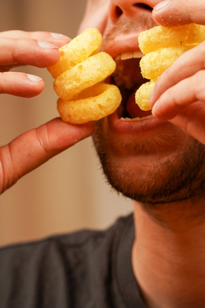 A golden ring-shaped snack held by a man shows off its crunchiness and exquisite appeal.の写真素材