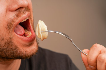 A close-up of a person savoring dumplings on a fork, highlighting the texture of the dish and the process of eating. Perfect for food-related concepts and culinary content.の写真素材