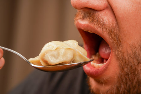 Man enjoying steamed dumplings, helping himself with a spoon. Great for cooking and lifestyle concepts.の写真素材
