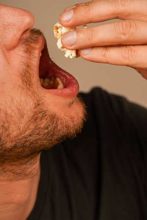 A close-up of a person eating popcorn with their hands, pouring it into their mouth. Demonstrating...