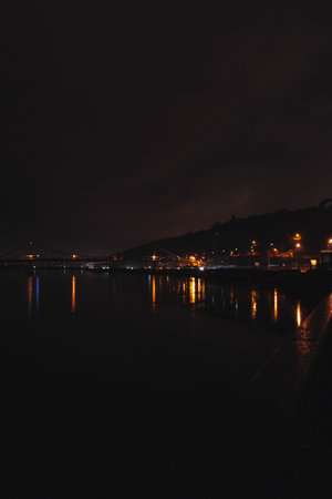The glowing bridge bends over the water at dusk. An impressive bright scene under a deepening blue sky.の写真素材