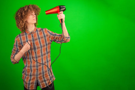 Radiating charm, the young man with bouncing curls confidently directs a hairdryer at himself on a...