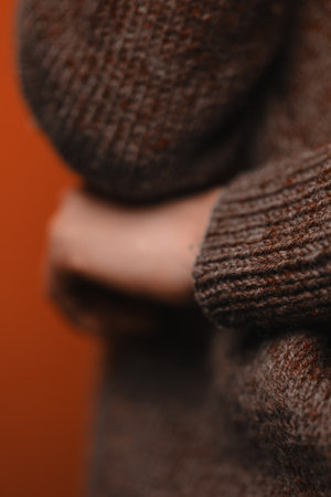 A woman in purple knitted sweater put her hand under elbow, without her face seen, closeup shot. Sign of closeness and uncertainty. Non-verbal sign language, vertical picture.の写真素材