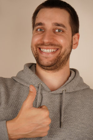 Young handsome man with beard over isolated gray background giving a thumbs up gesture.の写真素材