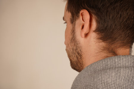 Neutral background. Male in casual clothes. Young guy standing in front of camera. Man looking at side. Head from back side. Side view. Handsome man.の写真素材