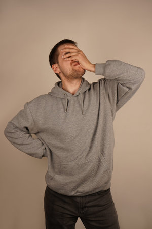 With his hand pressed against his face, the man shows a facepalm, indicating a moment of...