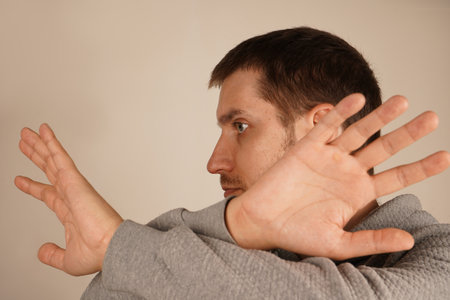 With arms crossed and fingers spread wide, a man creates a gesture of restriction or shielding. His open palms emphasize a defensive and assertive position. The image exudes caution and strength.の写真素材