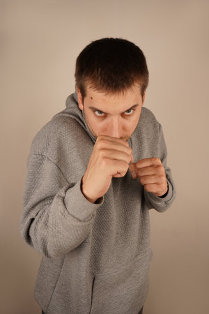 The mood is dynamic and intense. Wearing a sports hoodie, the man stands with fists clenched, prepared for action. His pose resembles that of a boxer, radiating energy and confidence.の写真素材
