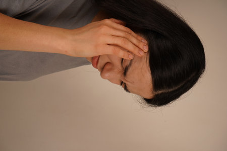 Her posture emphasizes the discomfort. The scene focuses on the need for pain management and alleviation. The woman touches her temple with one hand, signaling the agony of a bad headache.の写真素材