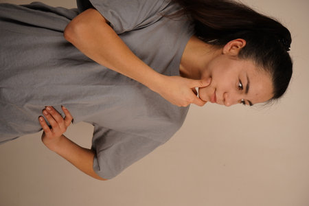 This pose depicts contemplation and inner concentration. With her chin resting on her hand, the young woman exudes a pensive air. Her relaxed posture and calm demeanor suggest a moment of reflection.の写真素材