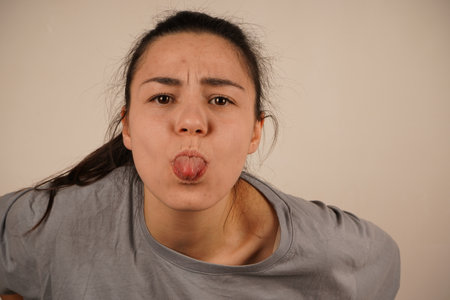 Her face is full of fun, capturing a light and humorous moment. It is a fun and playful reaction. With a playful expression, the girl sticks her tongue out towards the camera in a silly gesture.の写真素材