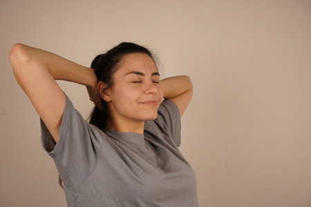 The pose demonstrates calm and tranquility. It is a gesture of relaxation and release of tension. With her hands resting on her head and her elbows bent, her pose conveys a sense of relaxation.の写真素材