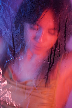 The transparent oilcloth reflects as she gently presses her hand against it, looking through it.