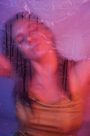 Close-up shot of a young girl surrounded by cellophane on a dark background. High quality photo.の写真素材
