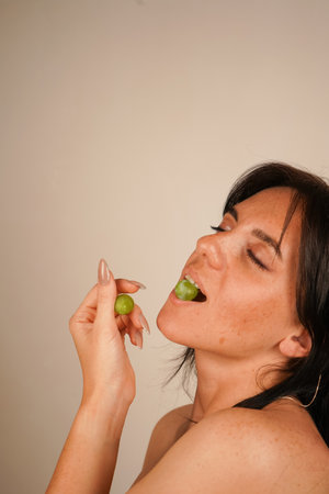The girls elegant hands holding the grapes emphasize the freshness of the fruit and her smooth, radiant skin.の写真素材
