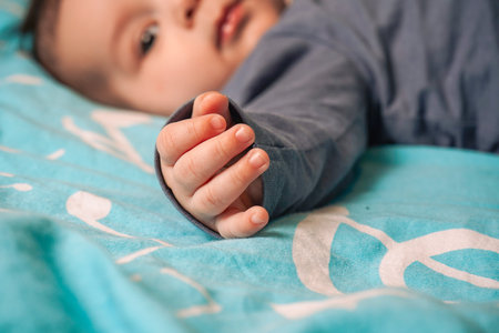Enjoying a peaceful moment, the child in a gray sweater and black pants rests still, lying...