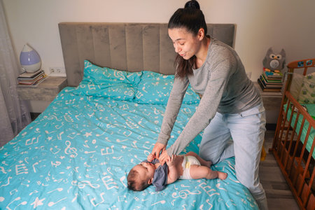 The baby waves its tiny arms and legs, gazing at its mother withの写真素材