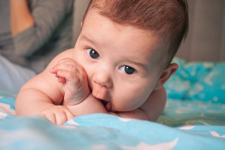 The child is lying on his stomach on the bed. Beautiful surprised child. Layout for advertising,...