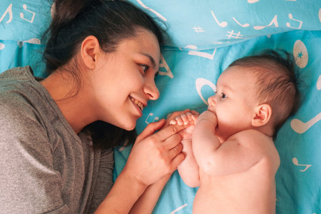 Happy mom lies peacefully on bed, hugging and cuddling her newbo