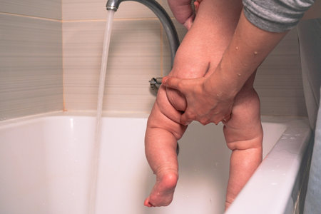 The mothers relaxed home attire-a loose, light-colored top and soft pajama pants-shows her focus on being present and nurturing for her little one.の写真素材