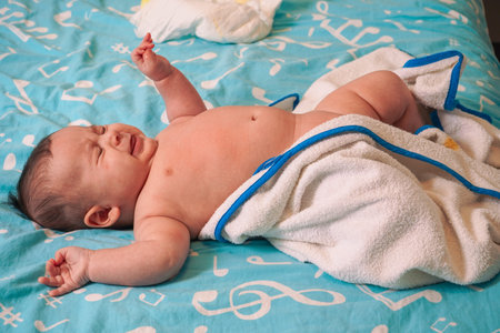 Cute little baby in towel after bath on bed at home.の写真素材