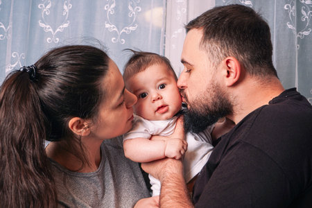 The fathers strong arms cradle the baby protectively while the mother gently supports the babys back, their synchronized gestures showing unity and love.の写真素材