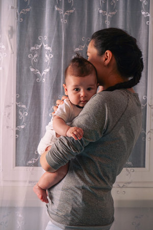 Beautiful young mother and cute newborn son in her arms.