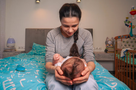 Mother holding head of her newborn son in hands. The baby on hands at mum. Loving mother hand holding cute sleeping newborn baby child.の写真素材