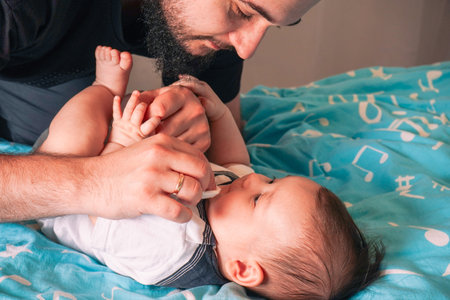 The baby lies peacefully on the blue blanket, enjoying the security of its fathers protective gaze.