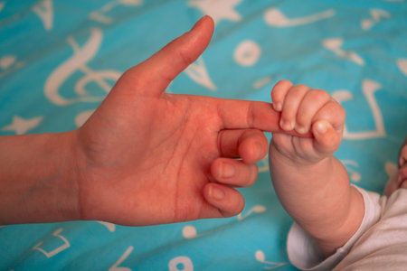 The baby grips a parents finger with all its strength, a sweet reminder of the bond they share.