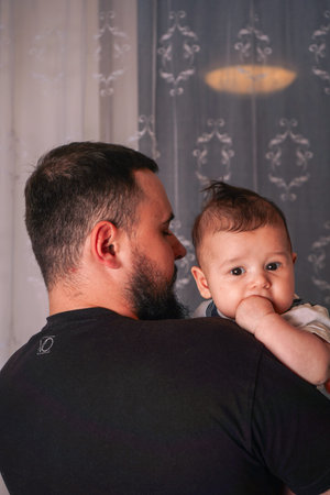 The father cradles his baby tenderly, while the childs gaze moves forward, capturing a timeless...