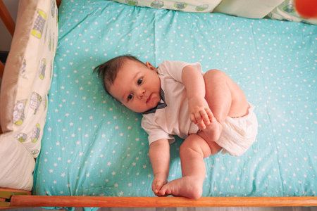 Little fingers squeeze the leg while the baby lies on its back in the crib, radiating peace and security.の写真素材