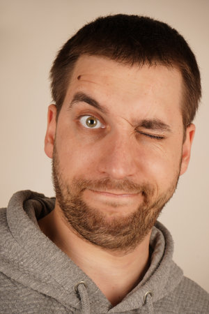 In this close-up, a young man's face displays an expression, with his eyes closed. His facial features are tense, clearly expressing his reaction to something.の写真素材