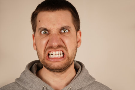 The image captures the power of his emotional outburst. A close-up of a mans face in intense anger, his mouth wide open, showing raw emotion. His expression conveys strong frustration and fury.の写真素材